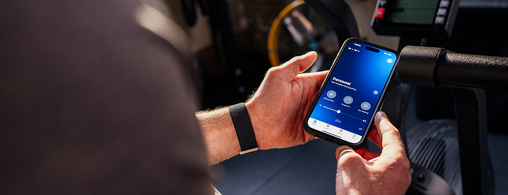 Image of male holding a smartphone showing the My Starkey app home screen